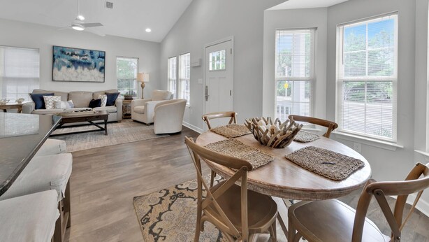 A spacious living area with a dining table, comfortable seating, and large windows. - Luna Sea-Walk to Beach-Seaside-Community Pool (Santa Rosa Beach)
