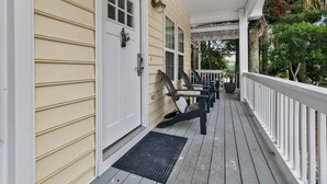 A covered porch with a wooden floor, a black metal door, and a white railing. - Luna Sea-Walk to Beach-Seaside-Community Pool (Santa Rosa Beach)