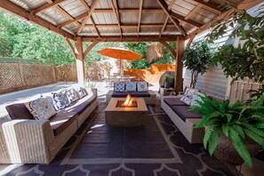 Une terrasse extérieure aménagée avec des meubles en osier, un foyer et une pergola.