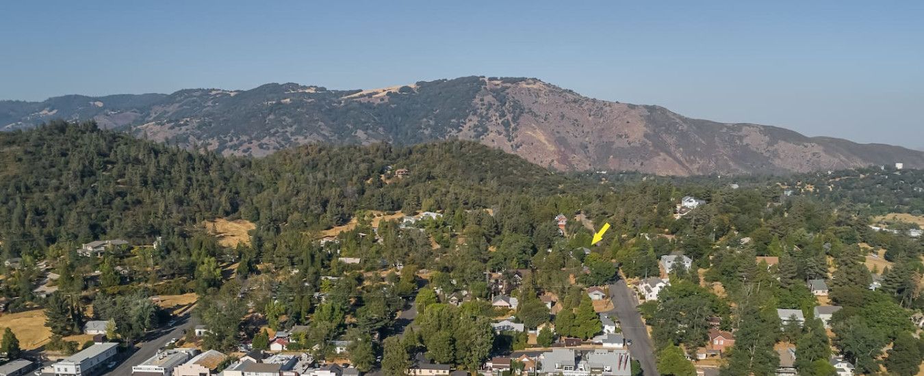 An aerial view of Main Street with residential houses, a parking lot, and a mountainous backdrop.