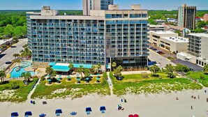 Een modern hotel met zwembad, een strandlounge en uitzicht op de omliggende stad.