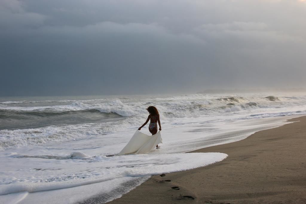 Una playa con olas y una persona caminando con una tabla de surf.