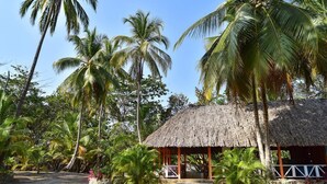 A thatched-roof hut surrounded by palm trees and a clear blue sky. - Playa Mareygua (Santa Marta)