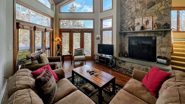 Un salón espacioso con chimenea de piedra, ventanas amplias y una zona de estar acogedora.