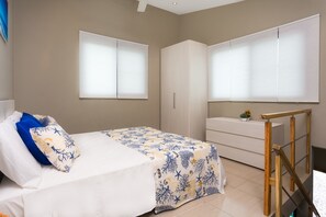 Une chambre à coucher avec un lit, une commode et une fenêtre équipée de stores.