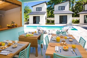 A breakfast setup with tables, chairs, and a pool area in a resort setting. - Residence Las Dos Palmas (Las Terrenas)