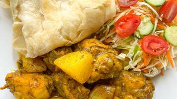 Une assiette contenant un plat de curry, du pain plat et une salade de légumes.