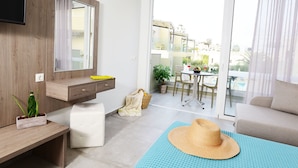A modern living room with a sofa, a TV, a wooden cabinet, and a balcony with a table and chairs. - Blue Horizon Apartments (Mylopotamos)