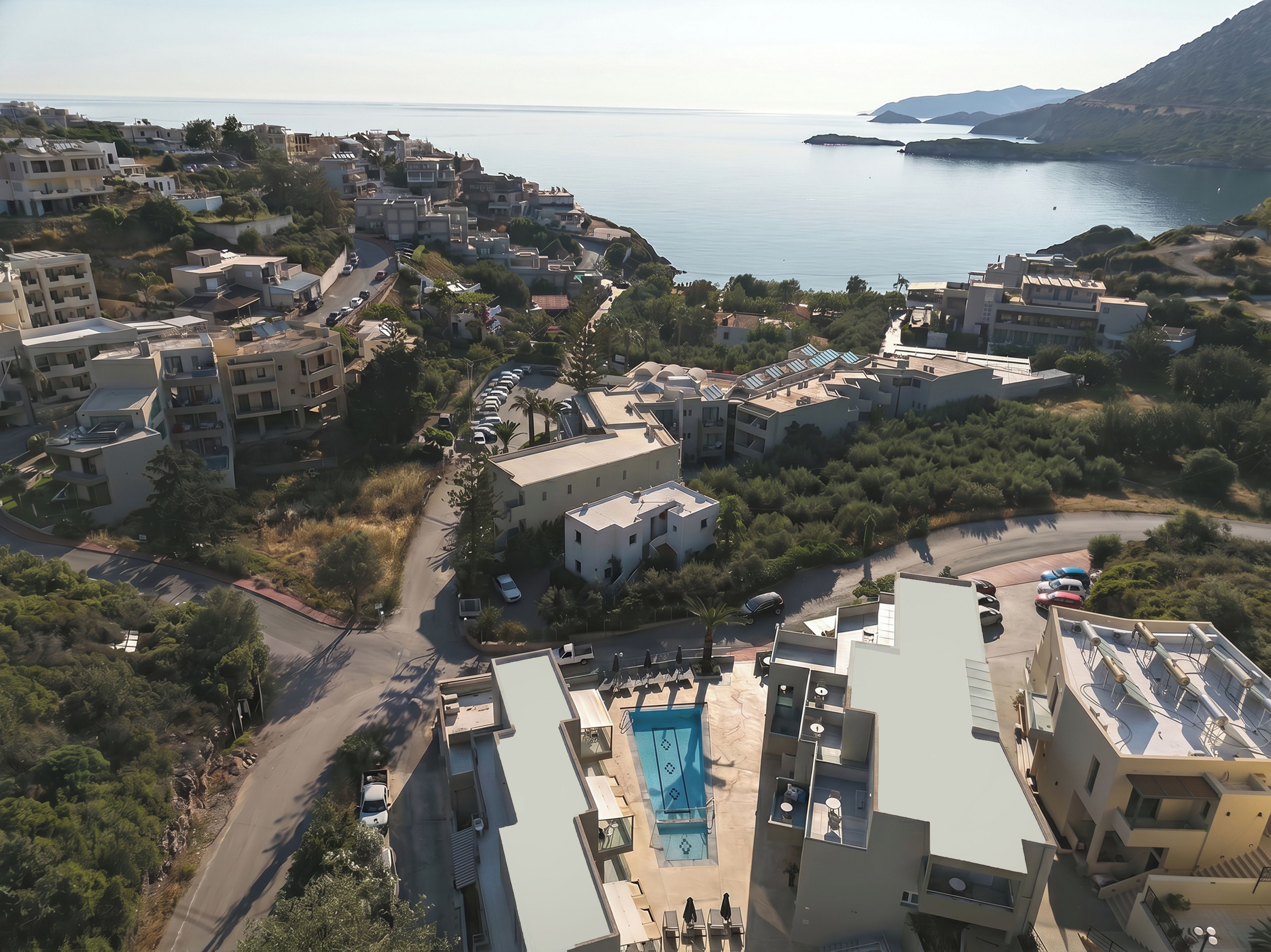A coastal residential area with modern buildings, a swimming pool, and a view of the sea.