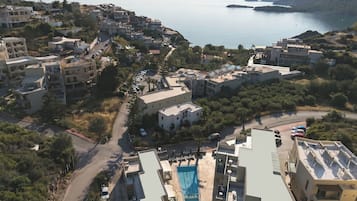 A coastal residential area with modern buildings, a swimming pool, and a view of the sea.