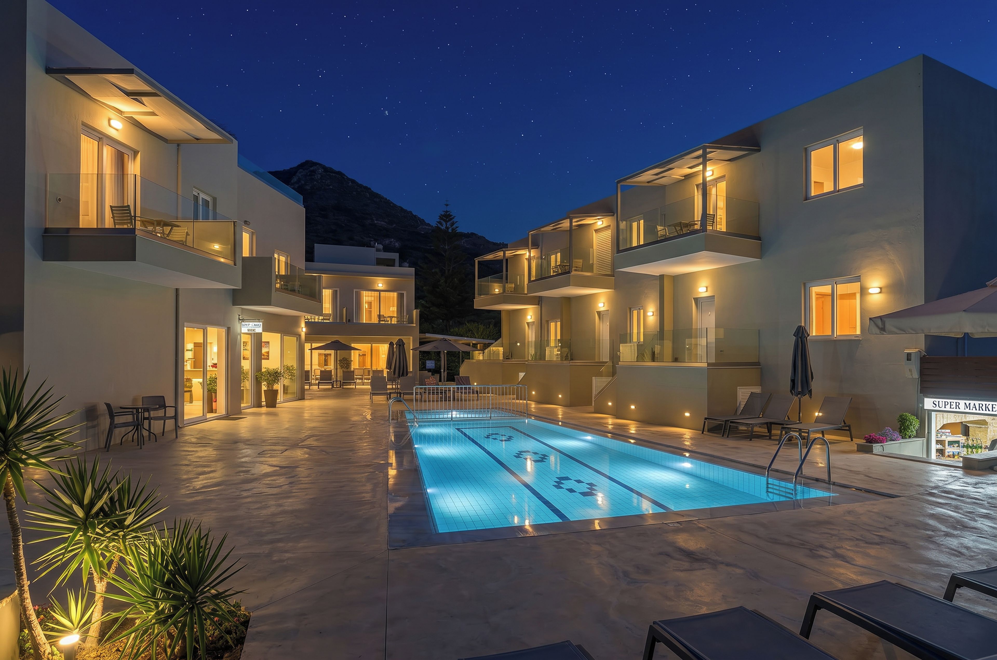 Un hotel moderno con piscina, asientos al aire libre y vistas a la montaña.