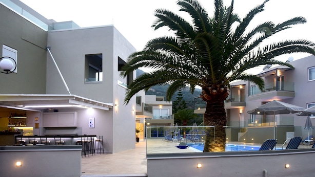 A modern hotel with a pool area, outdoor seating, and a palm tree. - Blue Horizon Apartments (Mylopotamos)