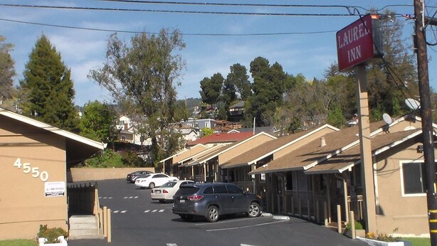 A street view of a motel with numbered parking spaces and a sign for 'LAUREN INN'. - Laurel Inn (Oakland)