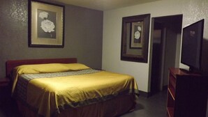 A hotel room with a bed, a dresser, and two framed pictures on the wall. - Laurel Inn (Oakland)