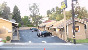 A hotel with a signboard, a parking lot with cars, and a building with a number '4550' visible. - Laurel Inn (Oakland)