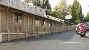 A motel with a row of rooms, a parking lot, and a satellite dish on the roof. - Laurel Inn (Oakland)