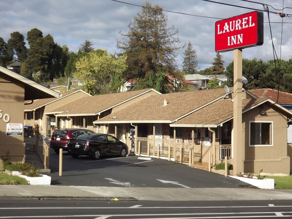 A motel with a sign reading "LAUREL INN" and a row of single-story buildings with a simple, functional design. - Laurel Inn (Oakland)
