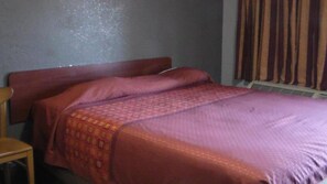 A standard hotel room with a single bed, a wooden chair, and a plain wall. - Laurel Inn (Oakland)