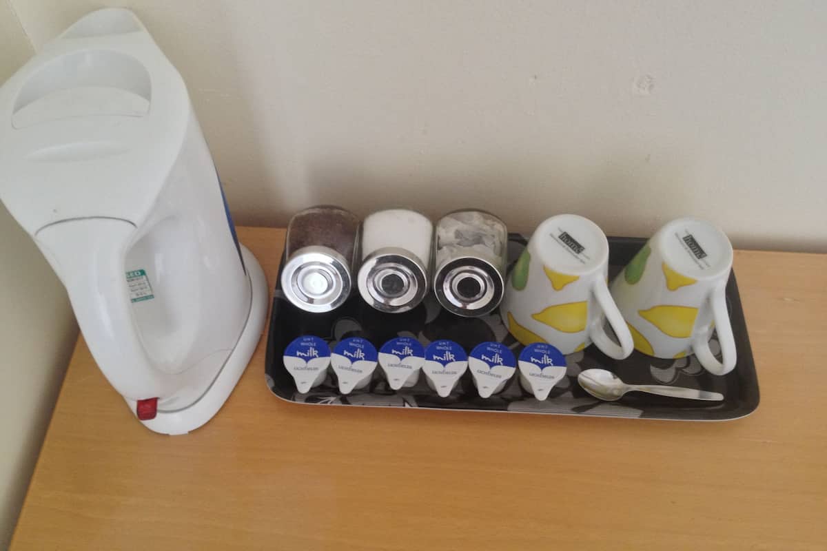 Una bandeja con una cafetera, tres latas y varias cajas de leche.