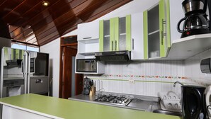 Una cocina con gabinetes verdes, microondas, estufa y cafetera.