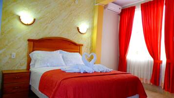 A hotel room with a wooden bed, red curtains, and a marble wall.