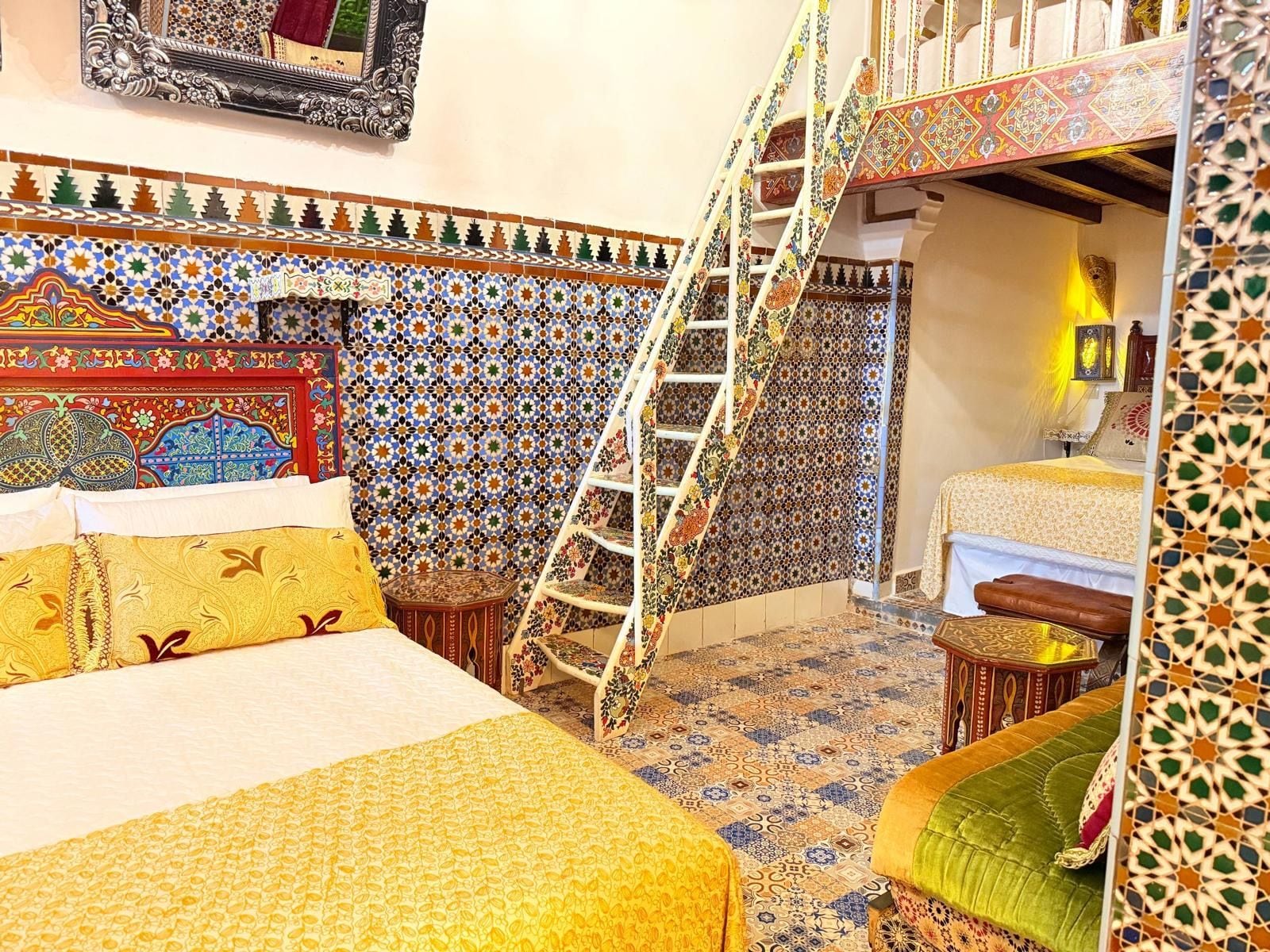 A room with a bed, a ladder, a small table, and a chair.