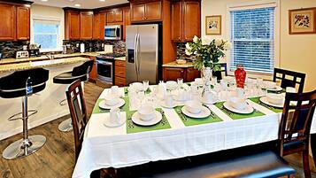 A modern kitchen with wooden cabinets, stainless steel appliances, and a dining area set for a meal.