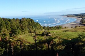 A coastal landscape with a road leading to a beach, surrounded by dense greenery.
