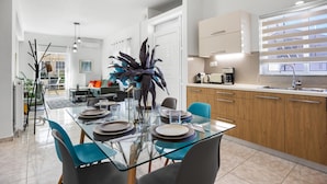 Una cocina moderna con una mesa de comedor de vidrio, sillas azules y armarios de madera.