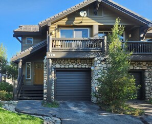 Une maison à deux étages avec une façade en pierre, un balcon et une porte de garage.
