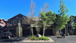 A residential area with a stone house, a parked car, and a motorcycle.