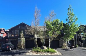 A residential area with a stone house, a parked car, and a motorcycle.