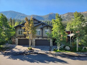 A two-story house with a stone foundation, a garage, and a driveway leading to the entrance.