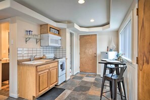 A kitchen with a wooden countertop, white cabinets, a microwave, and a stove. There is a dining area with a table and chairs. - Brookings Vacation Rental Studio - Walk to Town! (Brookings)