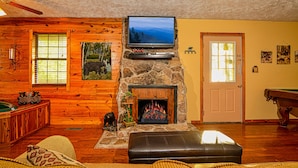 A cozy cabin interior with a stone fireplace, a mounted television, wooden walls, and a pool table. - Gatlinburg Cabin, Tickets, Heart Whirlpool, Hot Tub Pool Table King Bed Internet (Gatlinburg)