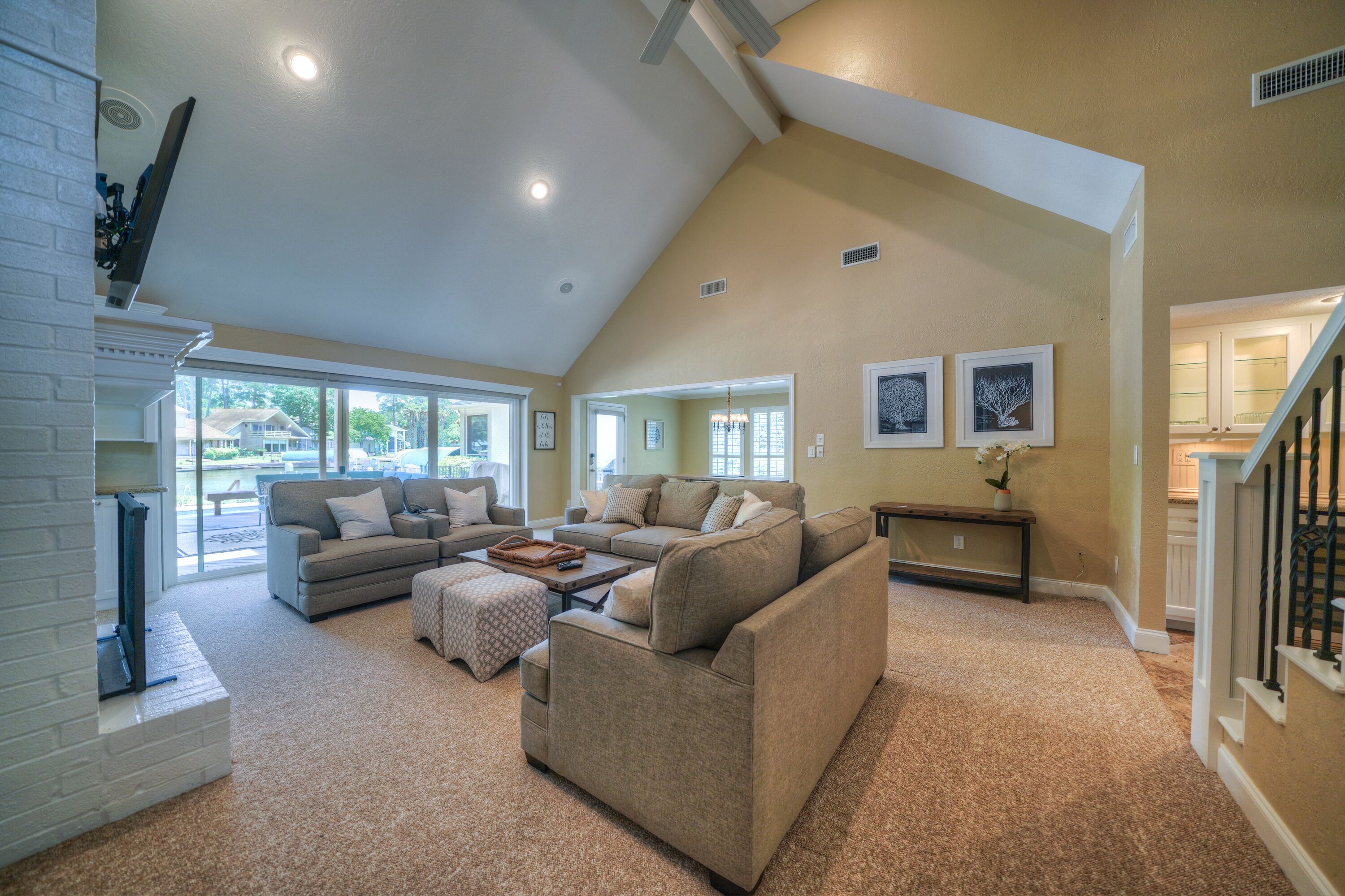 A spacious living room with a high ceiling, a fireplace, and a staircase leading to an upper level.