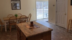 A kitchen with a granite countertop, wooden chairs, a dining table, and a framed picture on the wall. - Magnificent & Spacious Condo for All of Your PSU Vacations 4.5 Miles from Campus (State College)