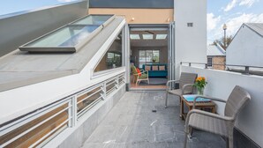 A rooftop terrace with a glass roof, a sofa, a chair, and a small table. - Designer house in quiet street on city doorstep (Darlinghurst)