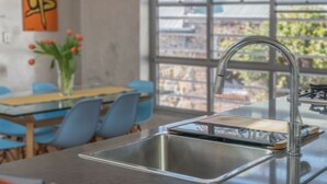 A modern kitchen with a stainless steel sink, a wooden cutting board, and a window with a view of buildings. - Designer house in quiet street on city doorstep (Darlinghurst)