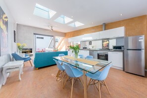 Eine moderne Küche mit einem Glastisch, blauen Stühlen und einem Edelstahl-Kühlschrank.