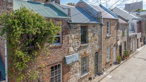 A row of stone buildings with metal roofs, some with satellite dishes, and a tree in front. - Designer house in quiet street on city doorstep (Darlinghurst)
