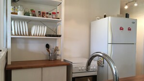 A kitchen with white cabinets, a stainless steel sink, a stove, and a refrigerator.