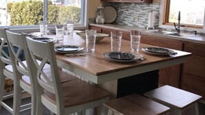 Uma cozinha moderna com uma ilha central, cadeiras brancas e um lustre.