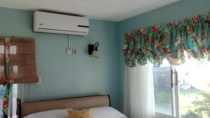 A room with a bed, an air conditioner, a wall-mounted light, and a window with floral curtains. - Habitacion moderna y acogedora de Azur (Kingston)