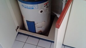 A water heater with a blue label, a valve, and a warning label. - Habitacion moderna y acogedora de Azur (Kingston)
