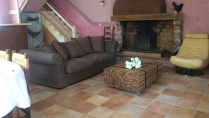 Una sala de estar con sofá, una mesa de centro de madera, chimenea y una escalera.