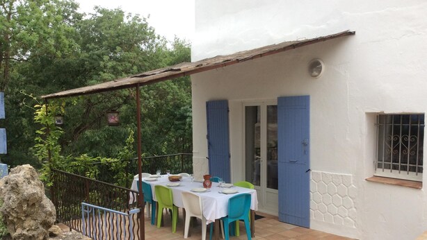 Un patio con mesas y sillas, un muro de piedra y una barandilla de metal.