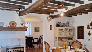 Ein rustikaler Essbereich mit Holztisch, Stühlen und einer Küche im Hintergrund.