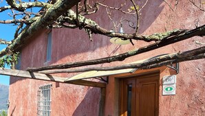 Ein rustikales Gebäude mit Holztür, einer Bank und einer Klingel.