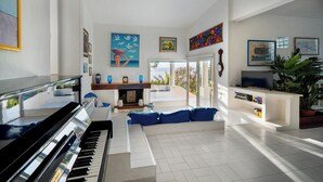 A spacious living room with a piano, a sofa, and a television. - Amazing sunset from the pool, 30 meters from the sea! (Torre Delle Stelle)